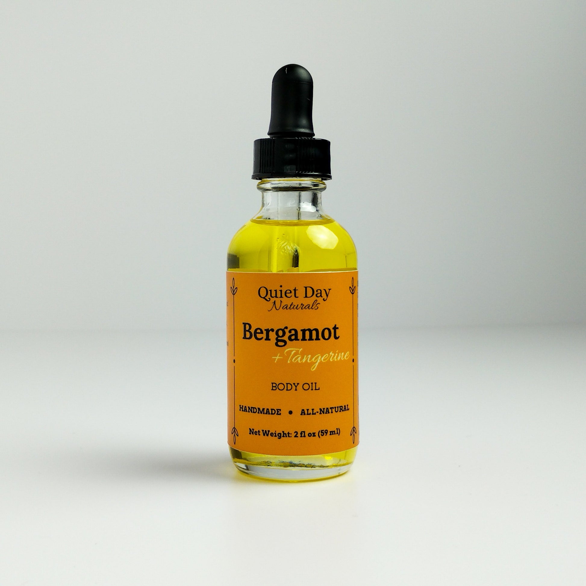 Bergamot and Tangerine Body Oil in a 2oz glass bottle with dropper standing against a white background.