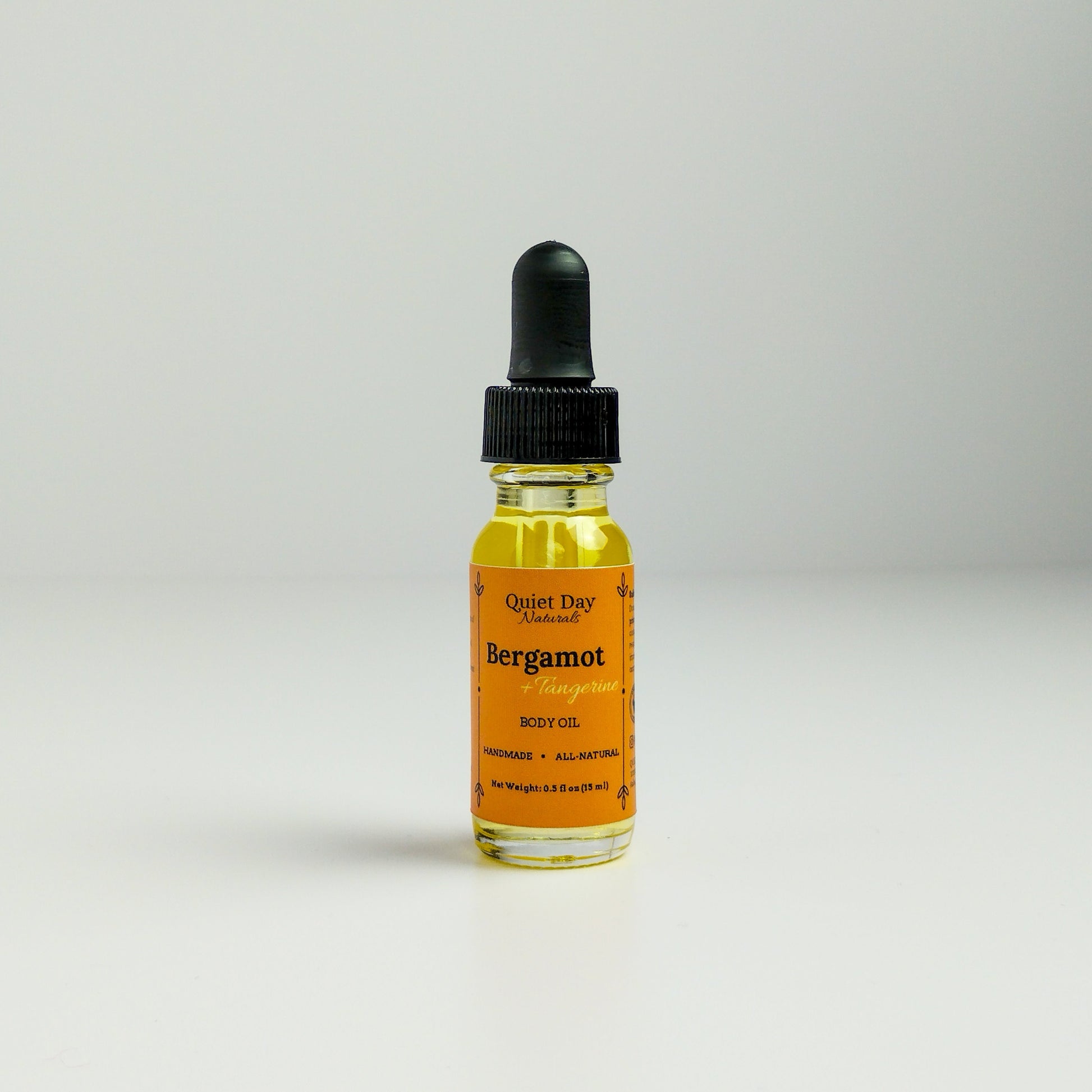 Bergamot and Tangerine Body Oil in a 0.5oz sampler glass bottle with dropper standing against a white background.