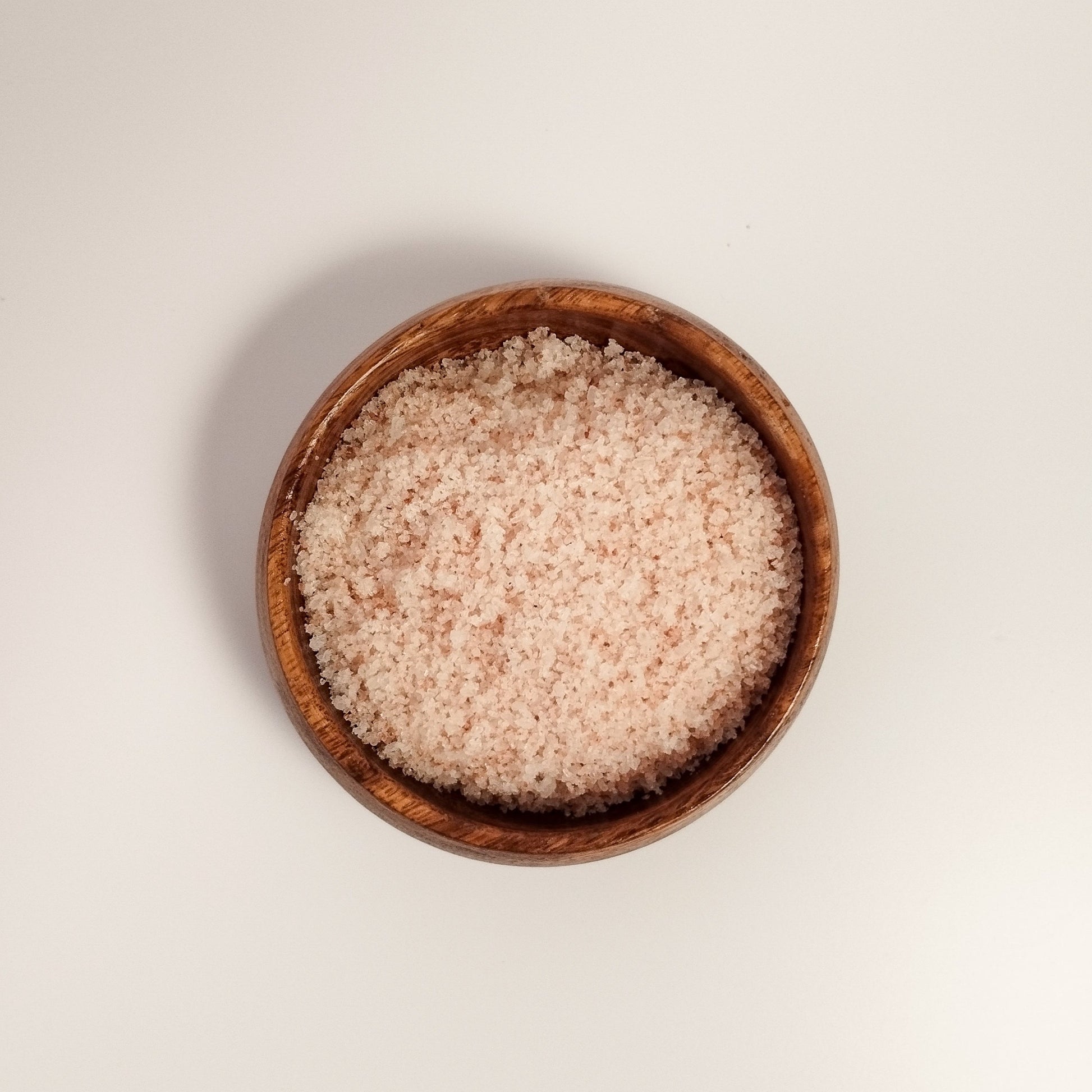 Close up of natural bath salt in a wooden bowl to show texture.