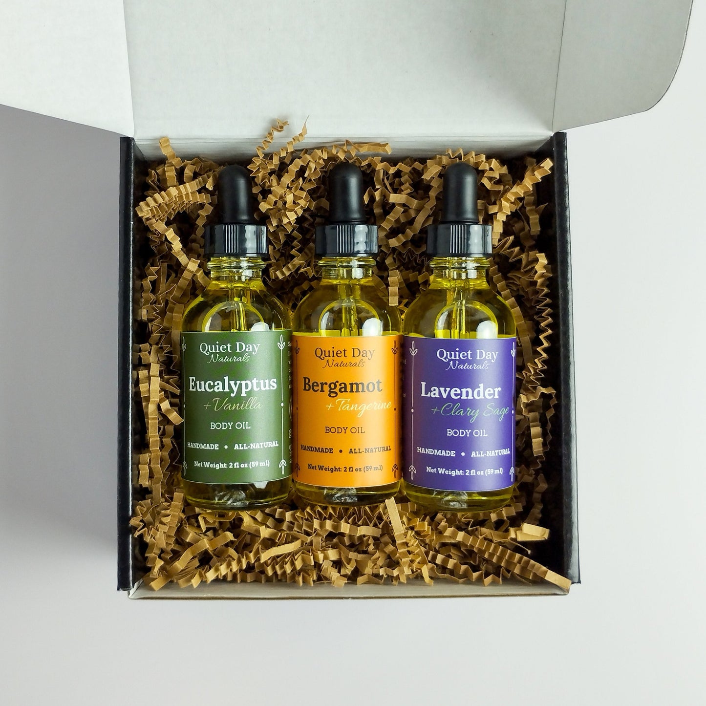 3 All-Natural Body Oils sitting in a gift box on a white background.