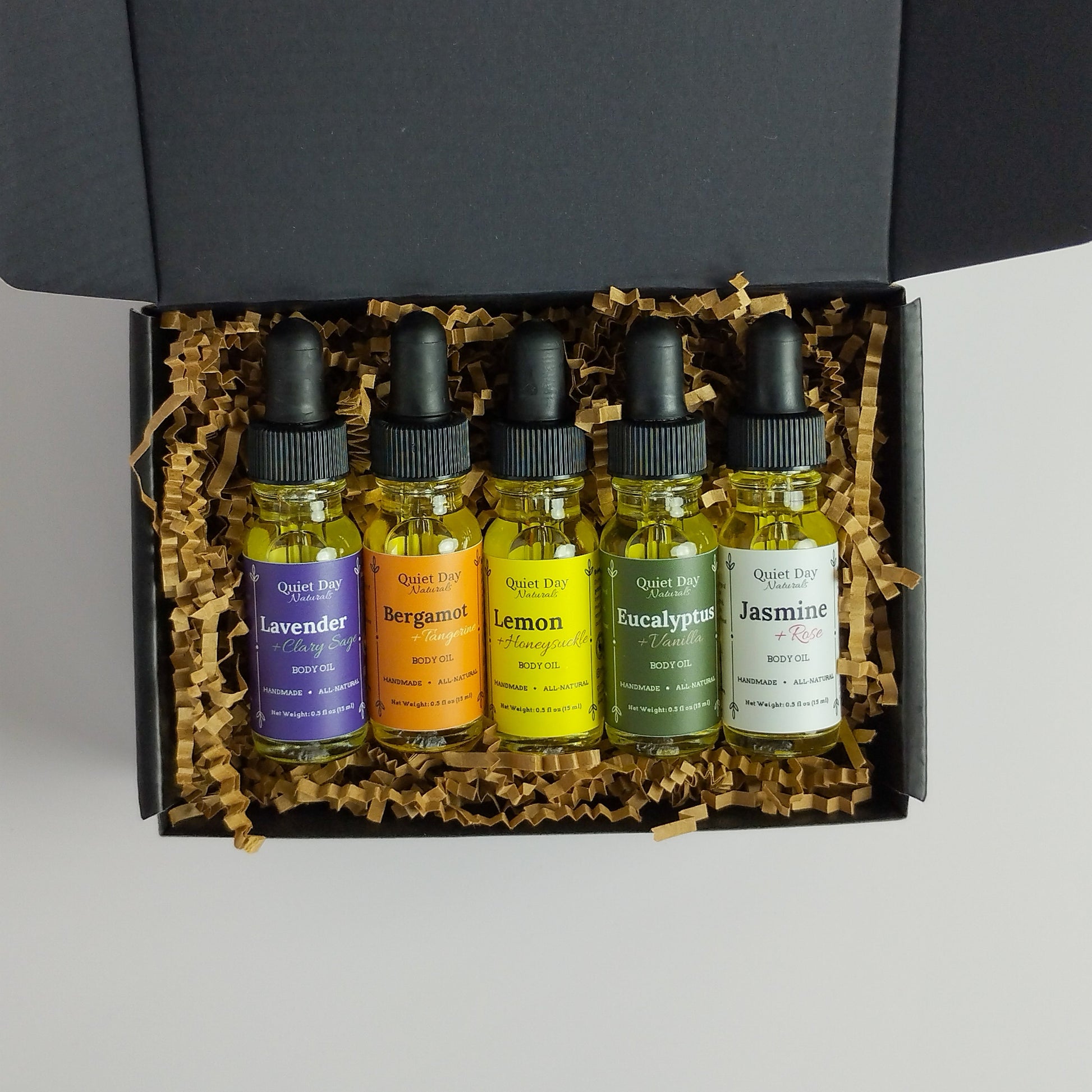 Natural body oils sitting in a black gift box against a white background.