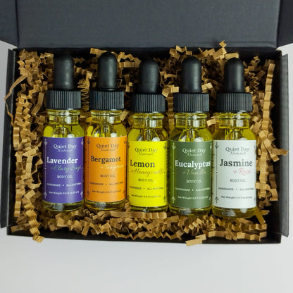 5-Pack Body oil Sampler pack with body oils sitting in a gift box against a white background.