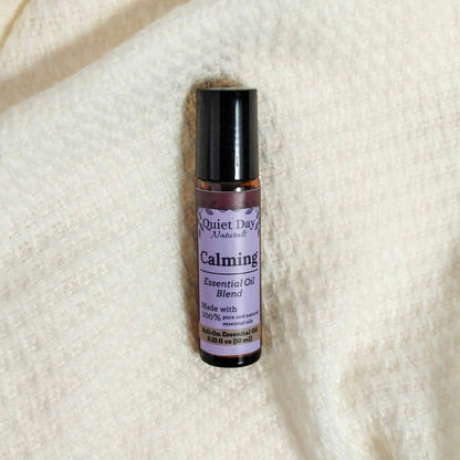 Cruelty free oil roller laying on a soft white blanket.