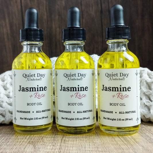 3 Natural Body Oils, Jasmine Scented sitting in front of a towel on a wooden background.