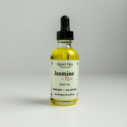 Jasmine and Rose Body Oil in a 2oz glass bottle with dropper standing against a white background.