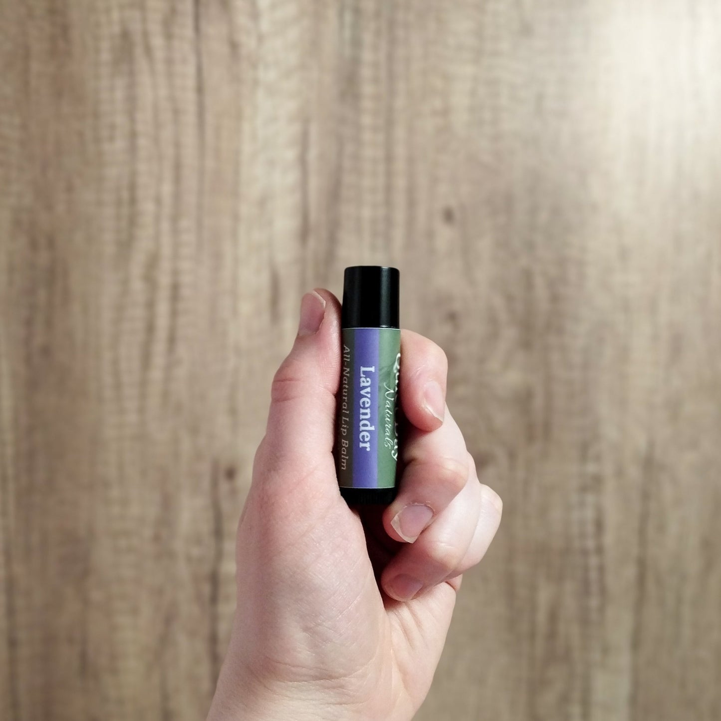 Paraben free lip balm being held in hand to show size.