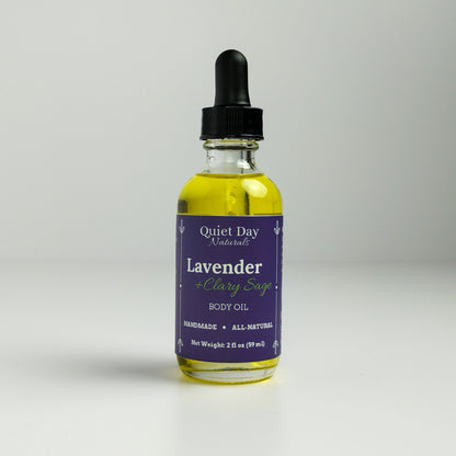 Lavender and Clary Sage Body Oil in a 2oz glass bottle with dropper standing against a white background.