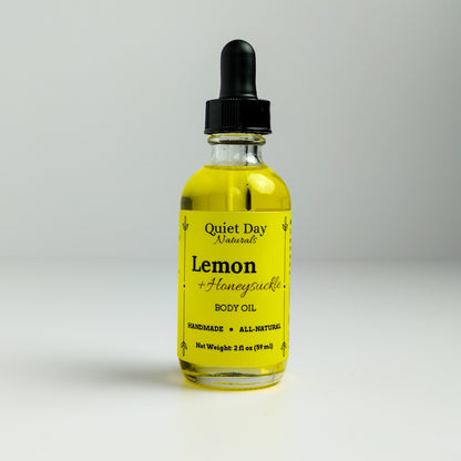 Lemon and Honeysuckle Body Oil in a 2oz glass bottle with dropper standing against a white background.