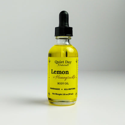 Lemon and Honeysuckle Body Oil in a 2oz glass bottle with dropper standing against a white background.