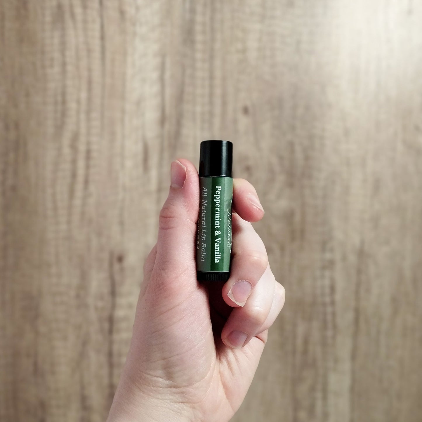 Paraben free lip balm being held in hand to show size.