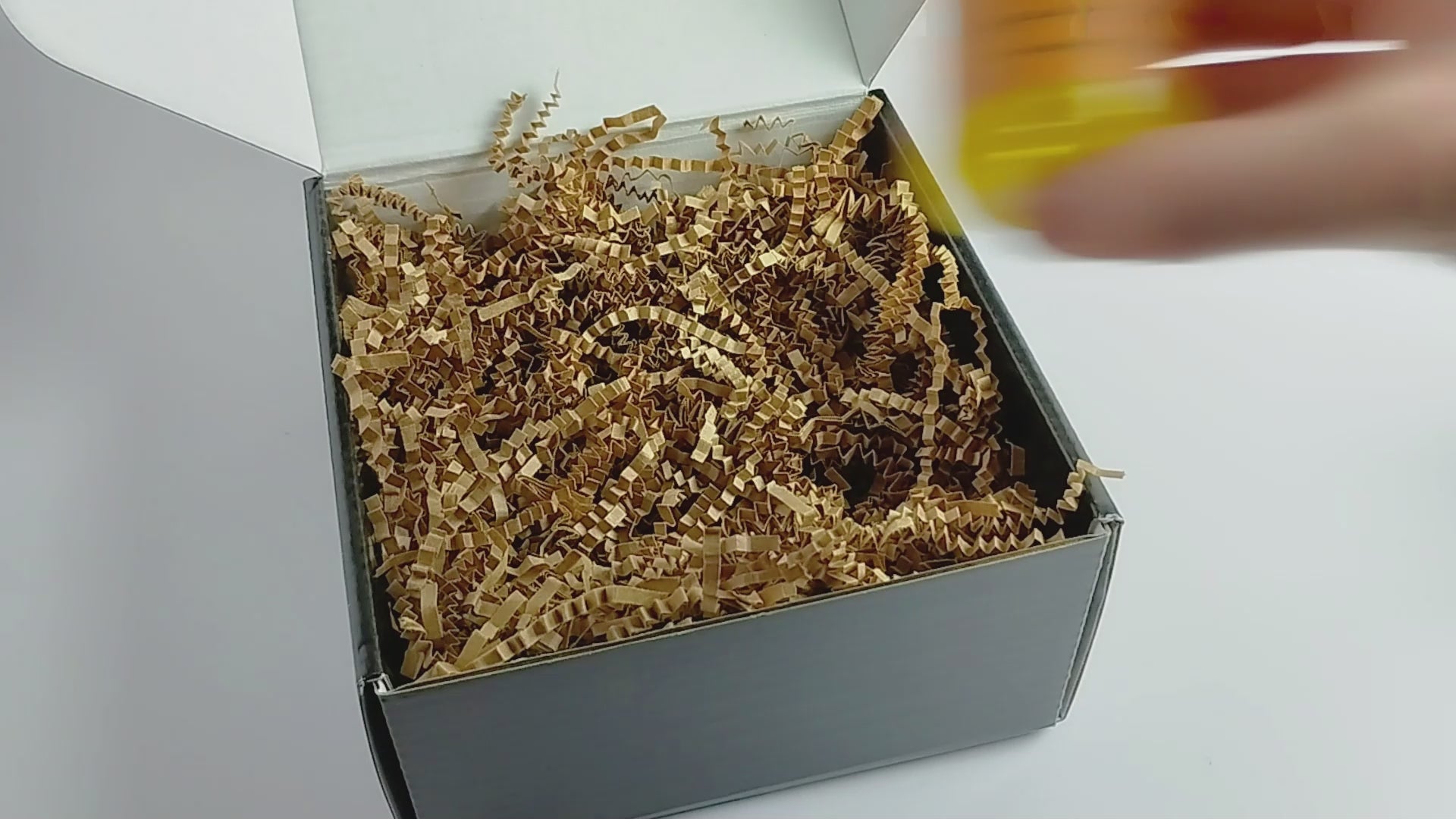 Video showing 3 2oz body oils getting packed into a black box with kraft crinkle paper. Close up showing 3-pack gift set.